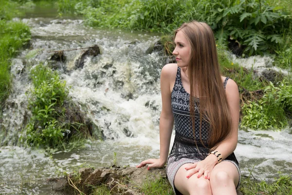 美丽的女孩坐在旁边的山溪 — 图库照片