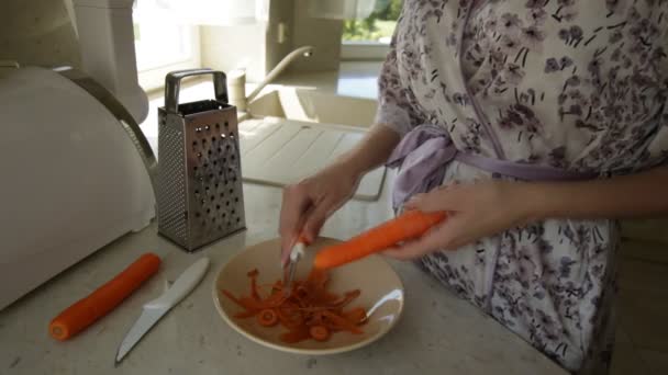 Mulher limpa cenouras na cozinha — Vídeo de Stock