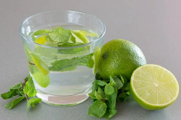 Cóctel Mojito con lima y menta en vaso sobre fondo gris —  Fotos de Stock