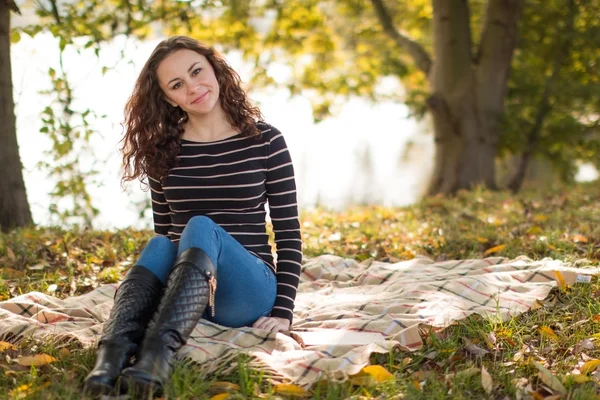 年轻女子在公园在秋天的毯子 — 图库照片