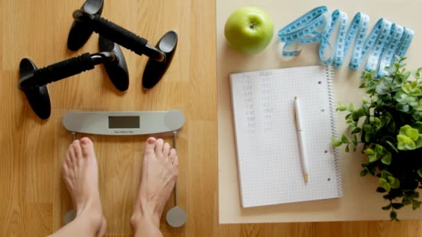 Concepto de fitness y pérdida de peso, báscula y cuaderno sobre una mesa de madera — Vídeos de Stock