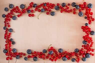 Çilek çerçeve ahşap arka plan üzerinde. Yaban mersini, kırmızı kuş üzümü