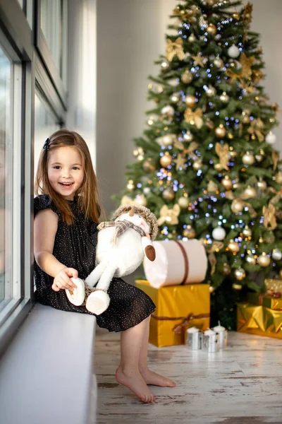 Petite fille mignonne avec bonhomme de neige s'amusant près de l'arbre de Noël intérieur. Joyeux Noël et bonne année — Photo