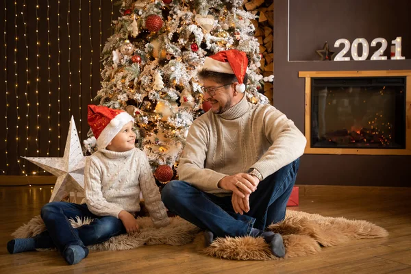 Far och son i julen hattar njuter nära julgran i inredda hem, Gott Nytt år 2021 — Stockfoto
