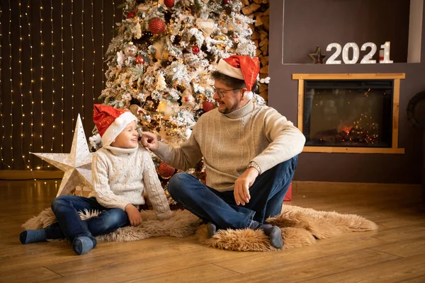 Far och son i julen hattar njuter nära julgran i inredda hem, Gott Nytt år 2021 — Stockfoto