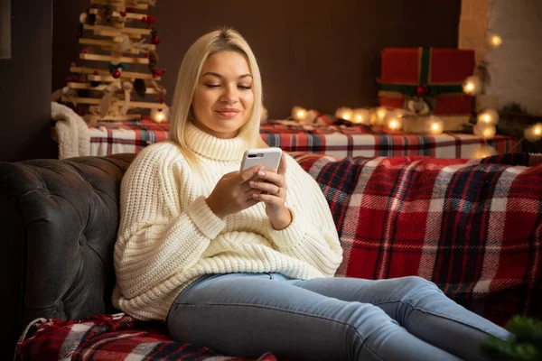 Gelukkig vrouw thuis het lezen van een sms-bericht tijdens het zitten op de bank in kerstvakantie, Gelukkig Nieuwjaar — Stockfoto