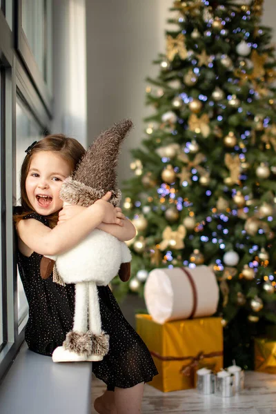 Cute small girl with snowman having fun near Christmas tree indoor. Merry Christmas and Happy New Year — Stock Photo, Image