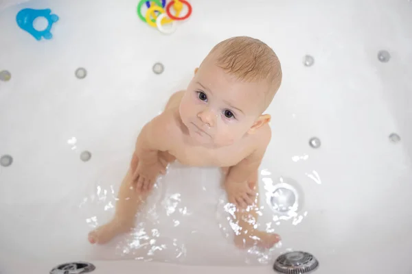 Söt liten flicka badar med leksaker och ler i stora vita bad — Stockfoto