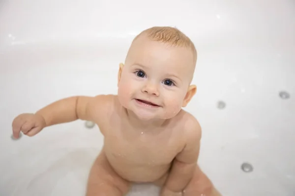 Cute baby girl bathing with toys and smiling in big white bath — Stock Photo, Image