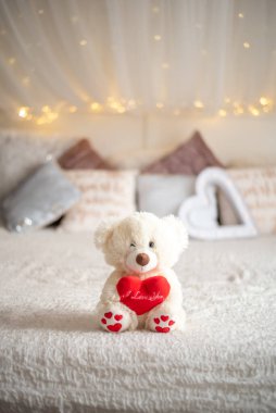Teddy bear hug heart pillow on bed, Valentines concept