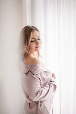 Erkek gömleği giymiş esmer kadın. Pencereden bakan genç bir kadının dikiz görüntüsü