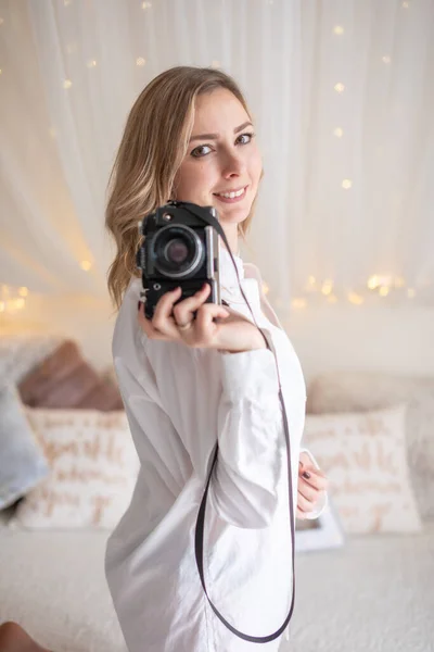 Sensuele vrouw neemt een foto van een oude camera in bed — Stockfoto