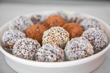Handmade coconut snow balls made from dates, almond and coconut truffles on grey surface
