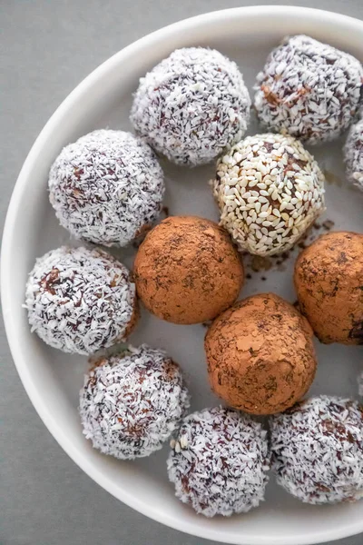 Handmade coconut snow balls made from dates, almond and coconut truffles on grey surface — стоковое фото