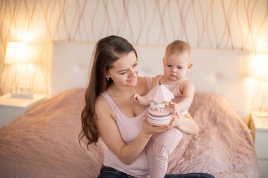 Genç, güzel bir anne ve küçük kızı yatak odasında el yapımı tahta oyuncaklarla oynuyorlar.