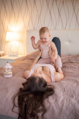 Genç, güzel bir anne ve küçük kızı yatak odasında el yapımı tahta oyuncaklarla oynuyorlar.