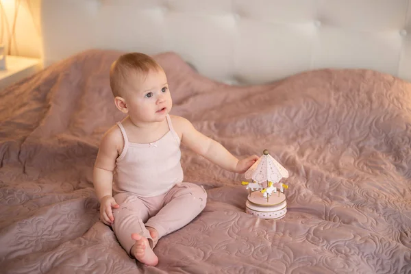 Linda niña jugando con juguetes de madera en el dormitorio de casa. Interior de vivero moderno en color rosa — Foto de Stock