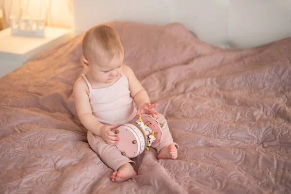 Linda niña jugando con juguetes de madera en el dormitorio de casa. Interior de vivero moderno en color rosa — Foto de Stock