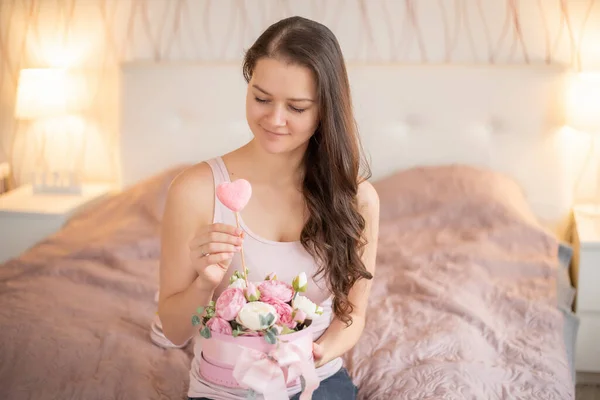 Mujer joven en cama rosa con flores - regalo para el 14 de febrero o el 8 de marzo —  Fotos de Stock