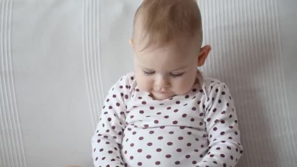 Sød baby pige sidder på sofaen og vinker arm, slowmotion video – Stock-video
