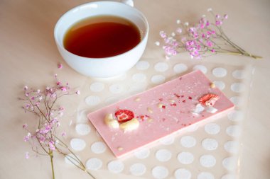 Taze ve kuru meyveli el yapımı çikolata ve açık ahşap masada sıcak çay.