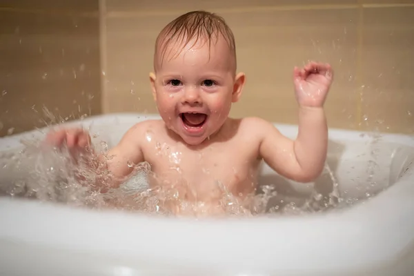 Liten charmig flicka babe leker i vattnet i små uppblåsbara baby pool som ligger i duschkabinen i badrummet, liten flicka ler och har kul — Stockfoto