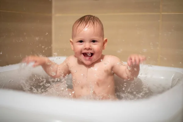 Liten charmig flicka babe leker i vattnet i små uppblåsbara baby pool som ligger i duschkabinen i badrummet, liten flicka ler och har kul — Stockfoto