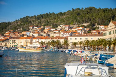 Vela Luka, Hırvatistan - 29,03.2021: Hırvatistan 'ın Korcula adasındaki eski kasaba arka planında Vela Luka limanındaki küçük tekneler