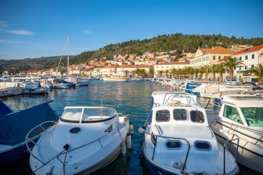 Vela Luka, Hırvatistan - 29,03.2021: Hırvatistan 'ın Korcula adasındaki eski kasaba arka planında Vela Luka limanındaki küçük tekneler