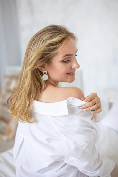 Portré egy gyönyörű érzéki fiatal nő szőke haj visel fehér inget otthon belső — Stock Fotó