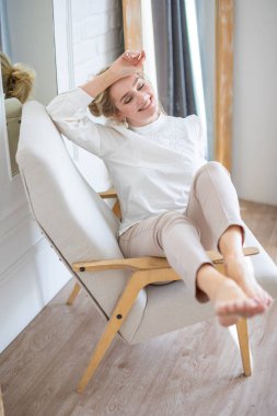 Evin içinde beyaz gömlek giyen, sarışın, güzel, şehvetli bir genç kadının portresi.