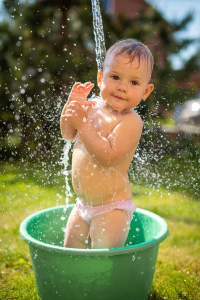 Baby flicka flopp i ett handfat med vatten på hemmaplan på sommaren — Stockfoto