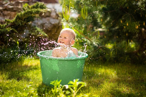 Девочка плюхнулась в тазик с водой на заднем дворе в летнее время — стоковое фото