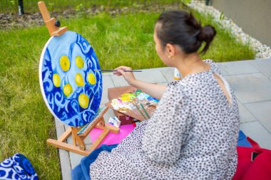 Asyalı genç bir kadın ev terasında resim yapıyor.