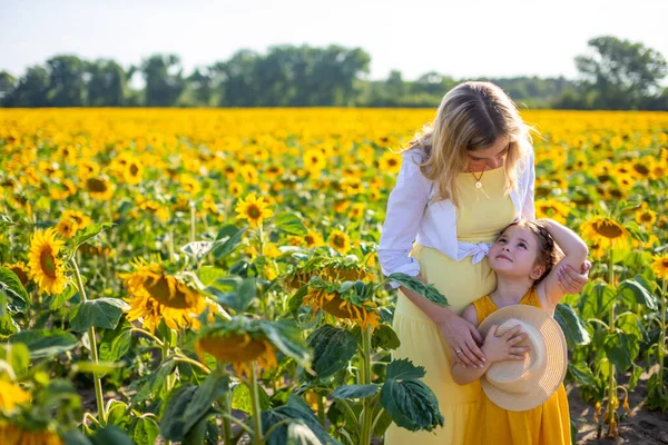 Счастливая мать с маленькой дочкой на подсолнечном поле — стоковое фото
