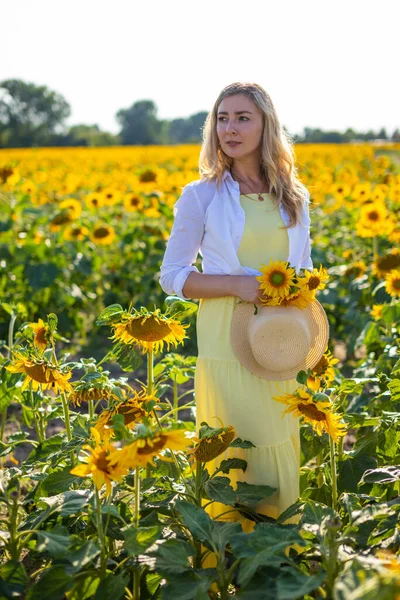 Portret van de mooie vrouw in zonnebloemen op een achtergrond van de lucht — Stockfoto