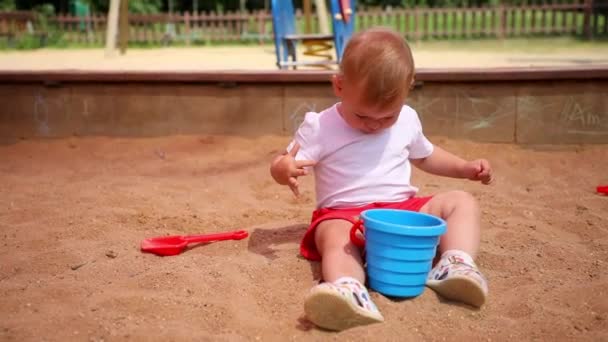 Adorable niña jugando con arena en arenero en el patio de recreo — Vídeos de Stock