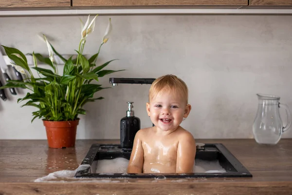 かわいいです幸せな赤ちゃん女の子とともに水と泡でAキッチンシンクにホーム — ストック写真