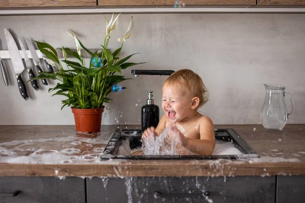 かわいいです幸せな赤ちゃん女の子とともに水と泡でAキッチンシンクにホーム — ストック写真