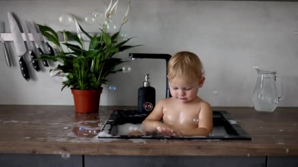 Carino felice bambina con giocare con acqua e schiuma in un lavandino della cucina a casa — Video Stock