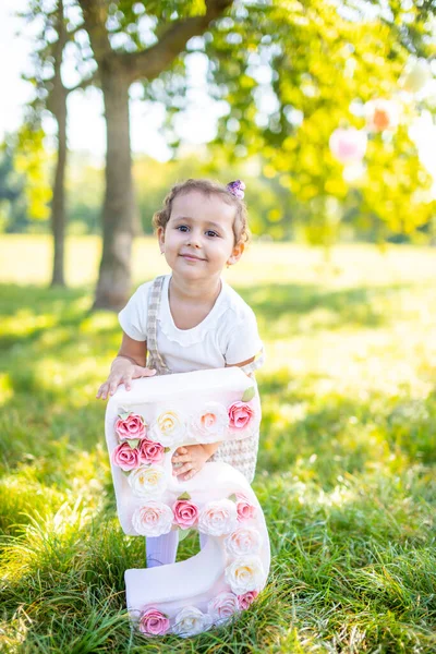 Весела дівчина розважається на день народження дитини на ковдрі з паперовими прикрасами в парку — стокове фото