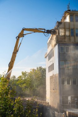 Sarı erişilebilir kazıcılı beton bir ofis binasının güçlü yıkımı. Dönüşüm, yıkım ve inşaat yenileme kavramı. Yüksek kalite fotoğraf