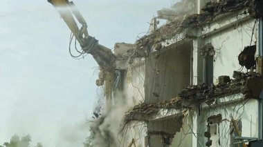 Yüksek erişimli bir kazıcı kullanarak eski bir ofis binasının yıkımı. Kentsel gelişim ve şehir dönüşümü. Yüksek kalite 4k görüntü