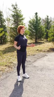 Sabah egzersizi sırasında parkta esneme hareketleri yapan bir kadın. Sağlıklı rutin, vücut hareketliliği ve aktif yaşam tarzı. Yüksek kalite 4k görüntü