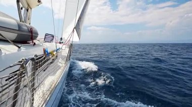 Denizi yarıp geçen bir yatın yanında Hırvatistan yakınlarında yelkenler açılıyor. Hareket, özgürlük, yelkencilik yaşam tarzı ve açık denizde macera. Yüksek kalite 4k görüntü