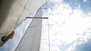 Hırvatistan yakınlarında yelken açarken rüzgar tarafından mavi gökyüzüne doğru esen tam beyaz yelkenler. Hareket, özgürlük ve yaz deniz yolculuğunun sembolü. Yüksek kalite 4k görüntü