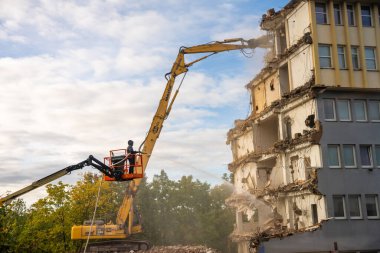 Prag, Çek Cumhuriyeti - 28 Eylül 2025: Tozu azaltmak için kısmen yıkılmış bir binaya su püskürten bir asansörde çalışan. Kentsel yıkım sırasında endüstriyel güvenlik prosedürü. 