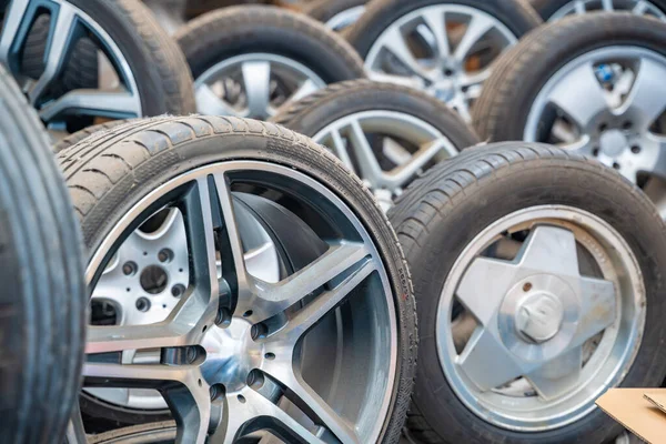 Araba atölyesinde arka arkaya dizilmiş lastikleri olan farklı araba tekerlekleri. Çek Cumhuriyeti 'nde kış hazırlıkları için mevsimlik lastik değiştirme ve servis. Yüksek kalite fotoğraf
