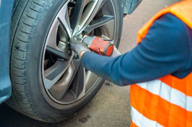 Tamirci, araba tekerleğindeki fındıkları sökmek için İngiliz anahtarı kullanıyor. Mevsimlik lastik değiştirme ve kış hazırlıkları için profesyonel araba servisi. Yüksek kalite fotoğraf