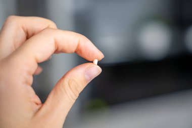 Yetişkin bir elin parmaklarının arasında duran bir süt dişinin makro görüntüsü. Görüntü, bir çocuk gelişiminde bir dönüm noktasını temsil ediyor. İlk dişini kaybetmenin duygusal anını yakalıyor..